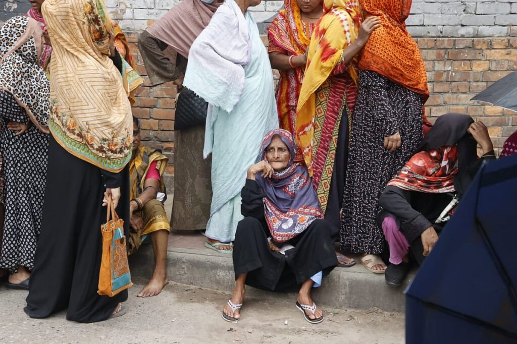 Elderly woman waits five hours in TCB queue, mother with infant stands nearby